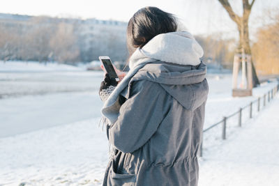 Woman holding mobile phone in snow