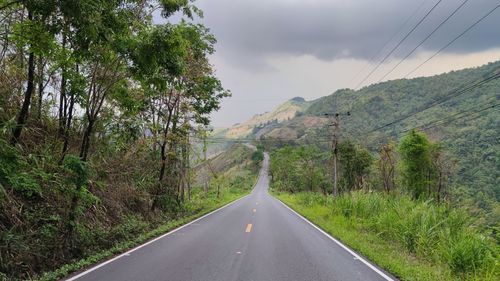 Road amidst trees against sky