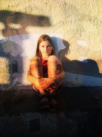 Portrait of woman sitting against wall