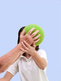 Midsection of man holding ball against clear blue sky