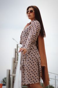 Young woman standing against sky