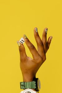 Close-up of man hand against yellow background