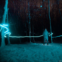 Man standing by tree in forest during winter