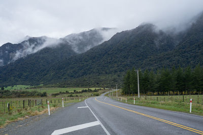 Scenic road in new zealand with mountains in background.