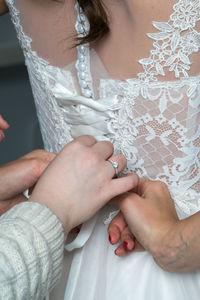 Cropped hands of woman dressing bride during wedding