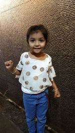 Portrait of a smiling girl standing against wall