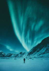 Person walking on snow covered mountain against sky at night