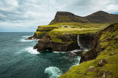 Scenic view of sea by cliff against sky