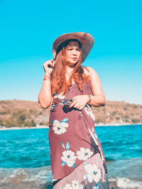 Young woman standing by sea against sky