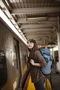 Woman looking at train while standing on railroad platform