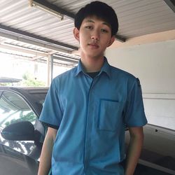 Portrait of young man standing by car