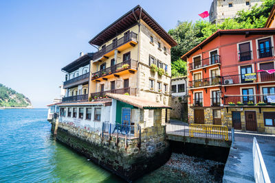 Buildings by river against sky