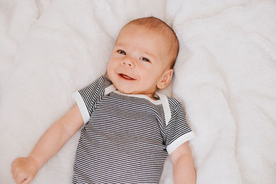 High angle view portrait of cute baby boy lying on bed