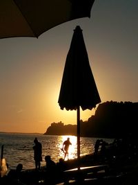 Silhouette people standing on beach against sky during sunset