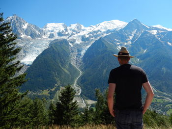 Rear view of man looking at mountains against sky