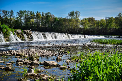 Scenic view of waterfall in forest against sky