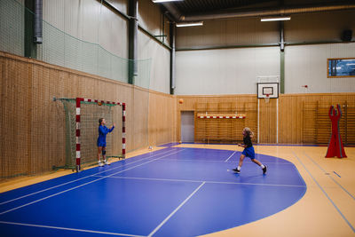 Girls practicing handball with each other in sports court