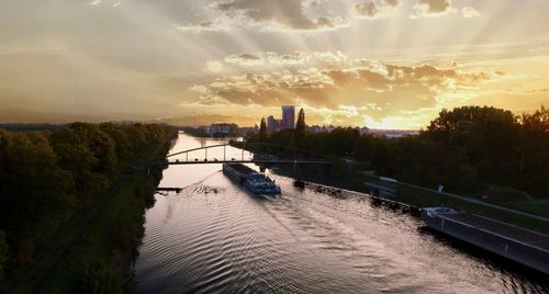 Bridge over river in city against sky during sunset