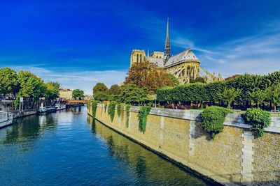 Seine river by notre dame de paris against blue sky