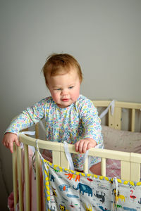 Cute girl of ten months old, playing alone in a crib at home in the afternoon or in the morning.