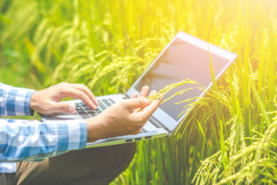 Midsection of man using laptop on field