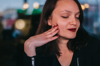 Close-up of young woman smiling with closed eyes while sitting at restaurant