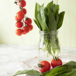 Ramsons and cherry tomatoes on marble work surface in a kitchen. healthy food concept