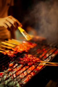 Midsection of man preparing food on barbecue grill