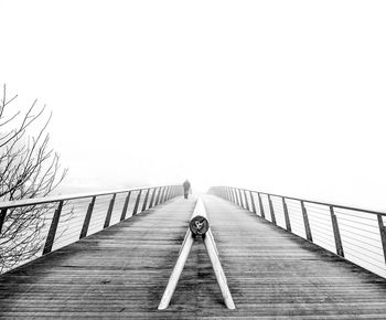 Distance view of man walking on bridge during foggy weather