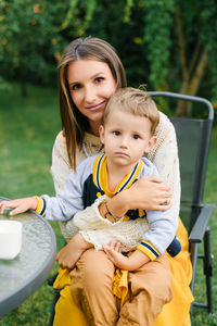 Tender portrait of a mother hugging her son while sitting outdoors in the garden, symbolizing love