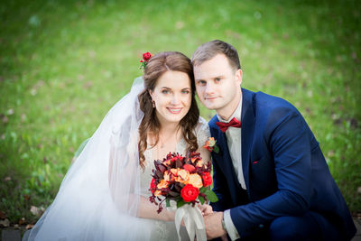 Portrait of smiling bride and groom holding bouquet