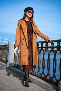 Full length of young woman standing by railing