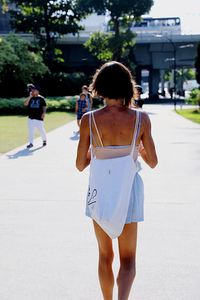 Rear view of woman walking on footpath in city