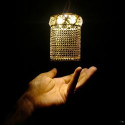 Close-up of hand holding candle against black background