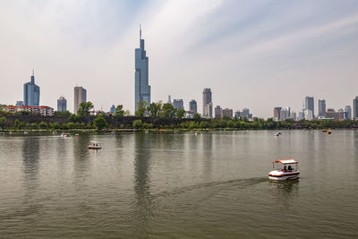 Nautical vessel on sea against modern buildings in city