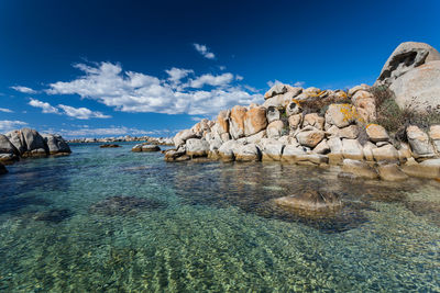 Rock formations in sea against blue sky