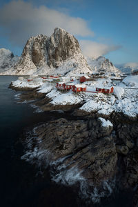 Stilt houses on mountains by lake against sky