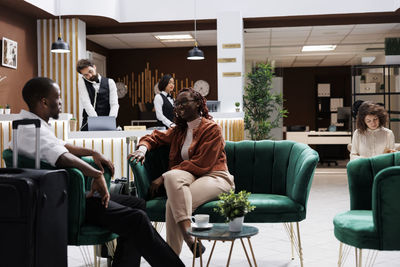 Side view of woman using mobile phone while sitting on chair