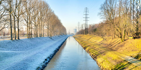 The emscher canal one side covered in snow, the other shone on by the sun in golden evening light.