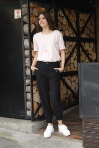 Portrait of young woman standing against wall