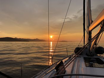 Sailboat sailing on sea against sky during sunset