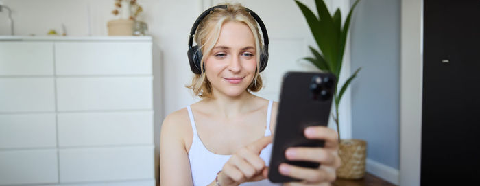 Portrait of young woman using mobile phone at home