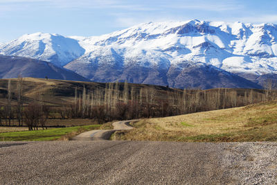 Road by snowcapped mountains against sky