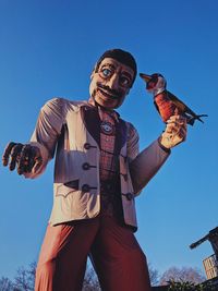 Low angle view of person standing against clear blue sky