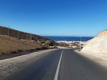 Road by city against clear blue sky