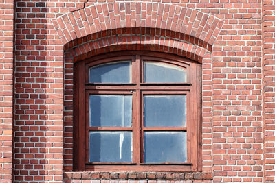 One arched glass window on old red brick wall. vintage window in brown wooden frame