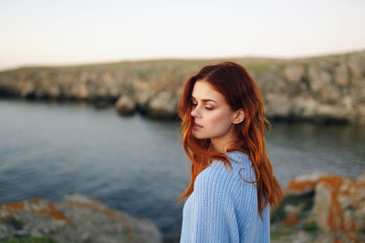 Portrait of woman standing against water