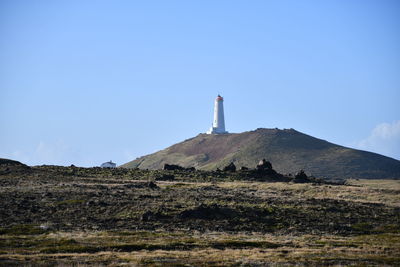 Low angle view of lighthouse by building against sky