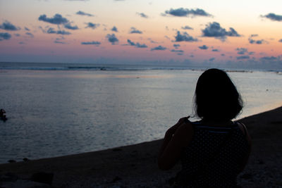 Rear view of woman looking at sea during sunset