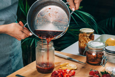 Fruit canning at home. woman pouring cooked jam into sterile jars. fruit preservation.